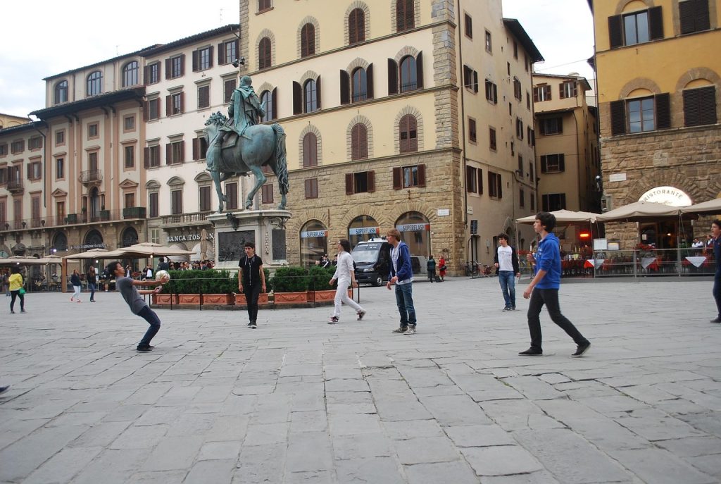 Young people playing with a ball in a plaza.